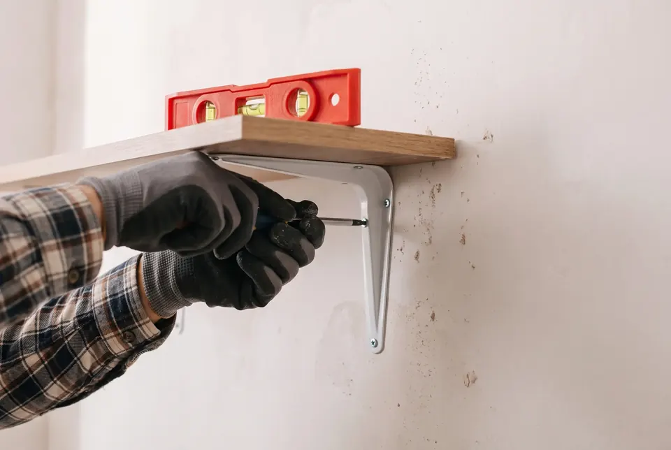 Mounting a floating shelf bracket to a wall during a handyman visit