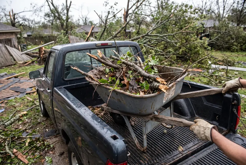 Loading storm debris into a truck bed for cleanup